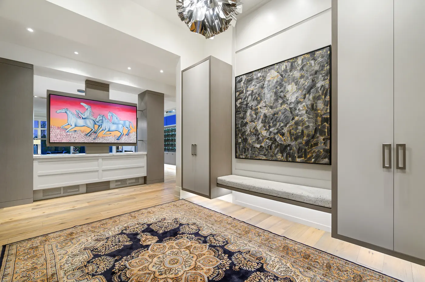 The foyer gallery in reverse, its crackle-cushioned floating bench and monumental black-and-gold abstract balanced by the galloping-horses canvas over the credenza beyond.