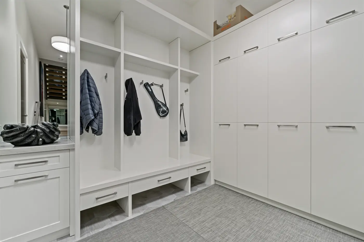 The mudroom's floor-to-ceiling white lockers, cubbies and bench drawers deliver family-scale organization off the garage entry.